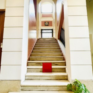 Petit monochrome monochrome rouge de Karine Corbier posé dans les escaliers de pierre du château des Arènes