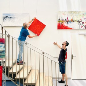 Accrochage du monochrome rouge de Karine Corbier par deux assistants techniques