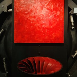 Peinture monochrome rouge de Karine Corbier posé au-dessus d'une turbine rouge sur fond noir au musée de la houille blanche