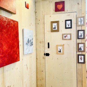 Photo de l'exposition avec des monochrome rouge un tableau de montagne et des petites aquarelle représentant des animaux sauvages
