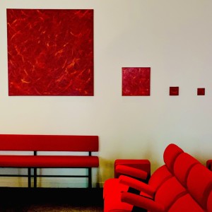 Série de monochrome rouge de différentes tailles dans la salle de spectacle du Moon Shot Lab Les tableaux dialoguent avec le rouge des fauteuils