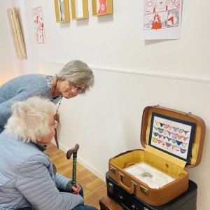 Vieille dame à une exposition de Karine Corbier devant un dessin de l'origine du monde placé dans une valise