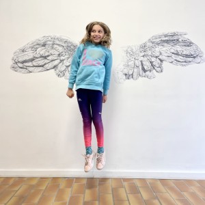 Jeune fille sautant en l'air devant les aies dessinées de Karine Corbier
